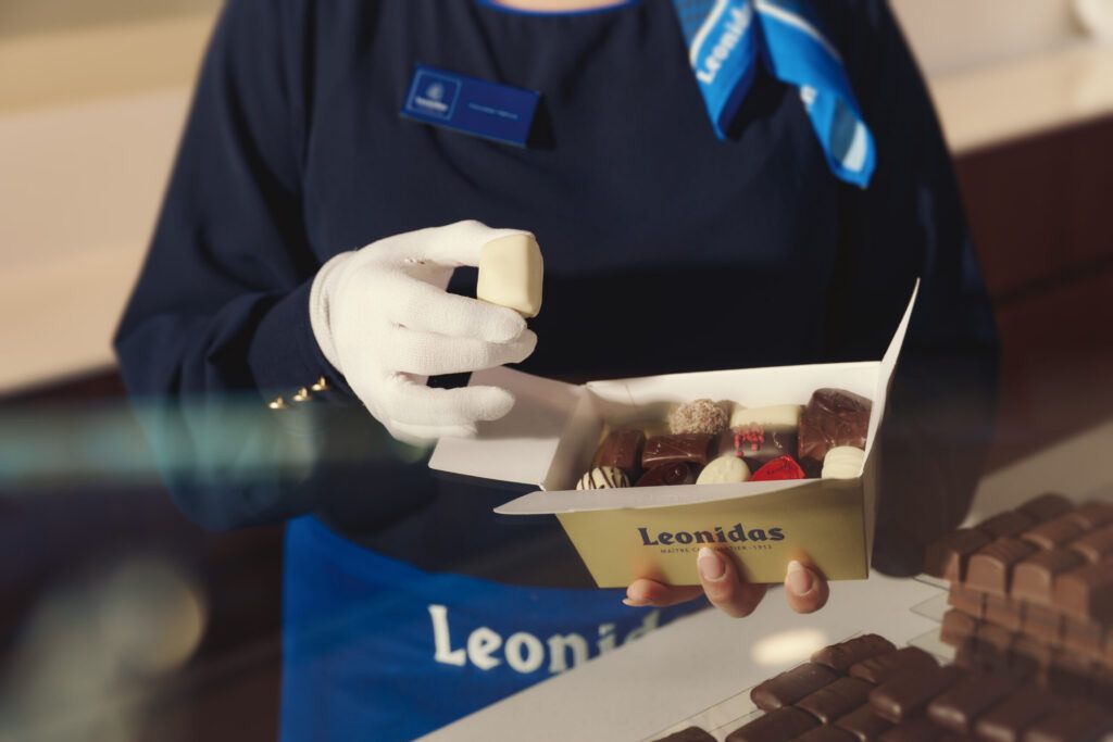 Un chocolat déposé à la main dans un ballotin